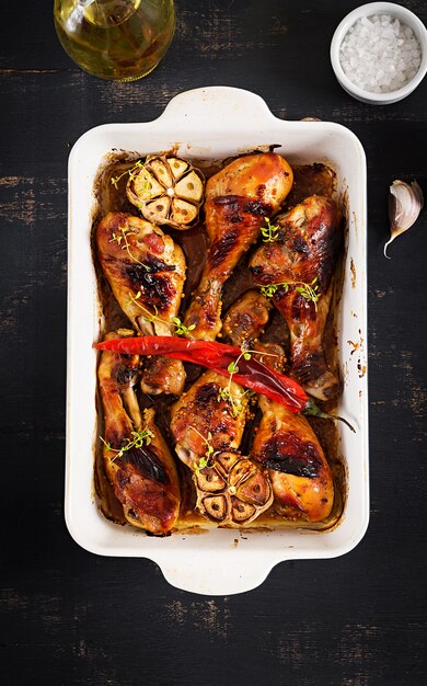 Bacchette di pollo dorate al forno appetitose al forno in una teglia su un tavolo scuro.
