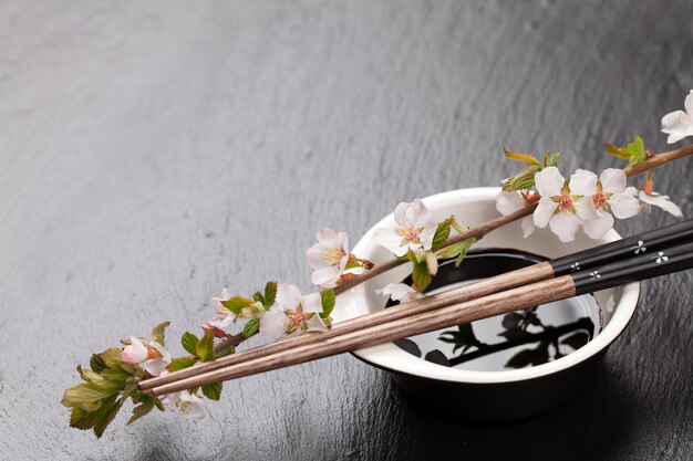 Bacchette di sushi giapponesi ciotola di salsa di soia e fiori di sakura