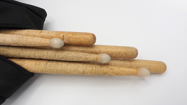 Bacchette di tamburo realizzate in vero materiale di legno e sacchetti di tessuto di colore nero con cerniera su sfondo bianco e studio isolato.