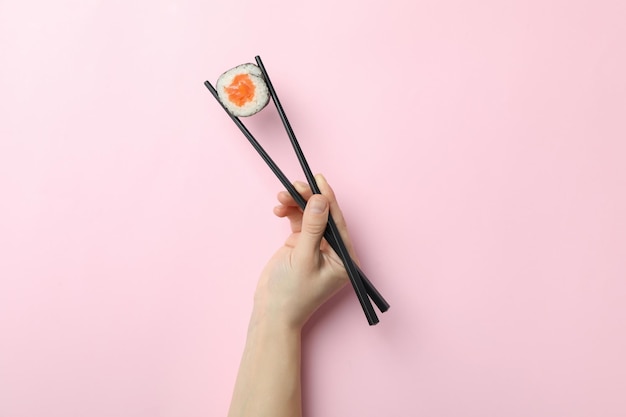 Bacchette femminili con maki su sfondo rosa