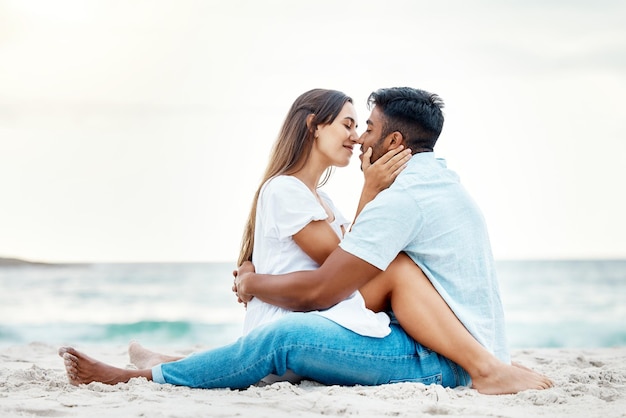 Bacio coppia spiaggia amore e felice luna di miele viaggio ed estate rilassante in riva al mare insieme Uomo romantico sorriso donna e giovani in vacanza sull'oceano vacanza intima e data di qualità