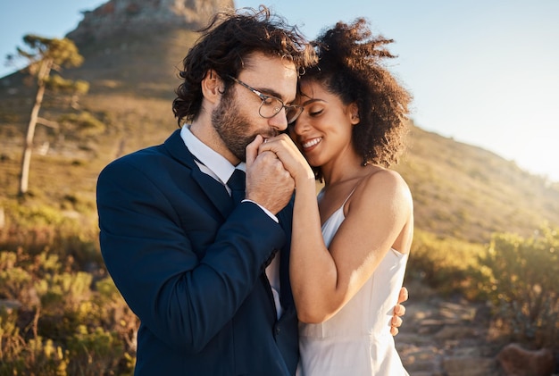 Bacio d'amore e matrimonio con coppia in natura per celebrare felicità e romanticismo Abbraccio al tramonto e affettuoso con gli sposi abbracciati in campagna per un matrimonio felice e sorridere insieme