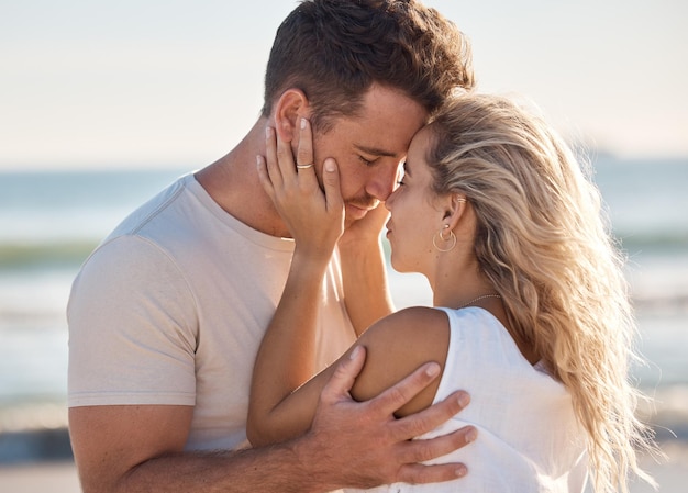 Bacio d'amore e spiaggia con una giovane coppia che condivide un momento intimo sulla costa in riva al mare o all'oceano Romanticismo nella natura e viaggio con un uomo e una donna che legano insieme in un appuntamento all'aperto in estate