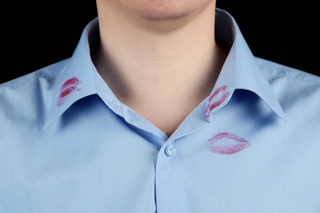 Bacio di rossetto sul colletto della camicia dell'uomo isolato sul nero