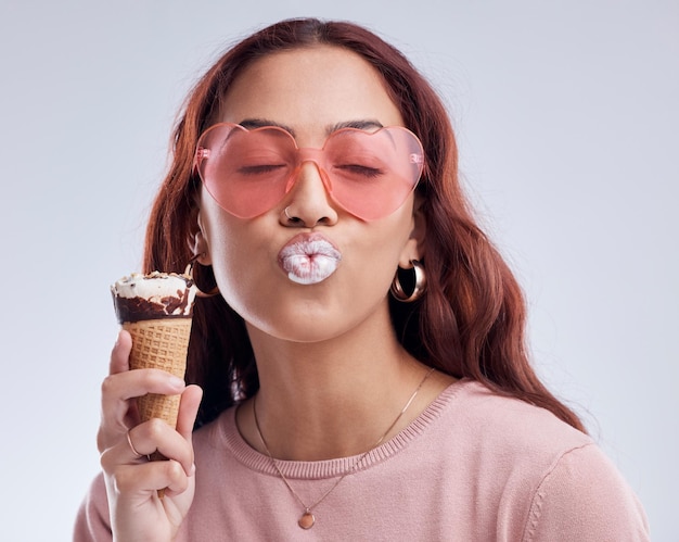 Bacio gelato e volto di donna con occhiali da sole in studio con spuntino dolce e dolci Baciare moda emoji e persona femminile con cono gelato in stile accessori alla moda e cosmetici