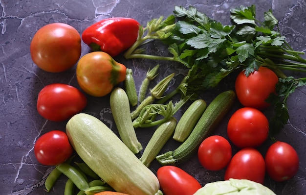 Background di cottura alimentare Rosmarino fresco cilantro basilico ciliegio pomodori peperoni e olio d'oliva spezie erbe e verdure a tavola di ardesia nera Ingredienti alimentari vista superiore