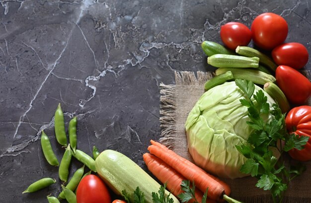 Background di cottura alimentare Rosmarino fresco cilantro basilico ciliegio pomodori peperoni e olio d'oliva spezie erbe e verdure a tavola di ardesia nera Ingredienti alimentari vista superiore