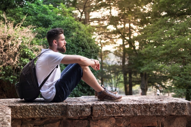 Backpacker, con la barba, seduto a godersi il tramonto in natura.