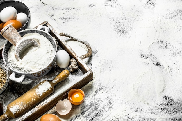 Backround di pasta. Farina con uova e mattarello. Sulla scatola di legno.