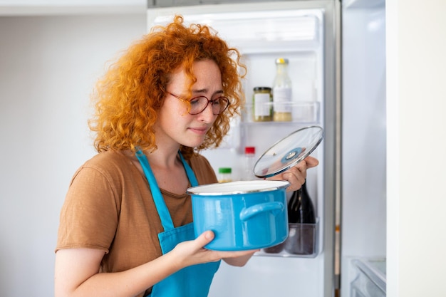 Bad Food In Fridge giovane donna che si tiene il naso a causa del cattivo odore del cibo nel frigorifero a casa