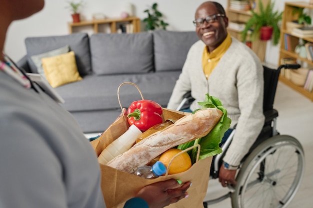 Badante che consegna cibo all'uomo con disabilità