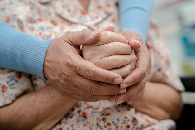 Badante che si tiene per mano Paziente asiatico donna anziana con amore cura incoraggiare ed empatia al concetto medico sano forte dell'ospedale infermieristico