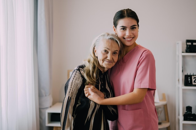 Badante felice e paziente anziano sorridente e guardando la fotocamera Donna anziana e medico a casa