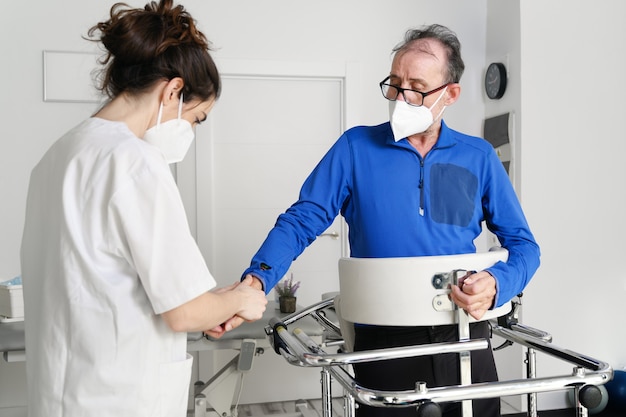 Badante infermiera femminile, tenendo la mano del paziente, supporto paziente disabile seduto sulla sedia a rotelle in ospedale, giovane assistente medico aiuta il paziente paralizzato.