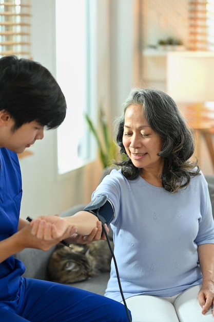 Badante maschio che controlla la pressione sanguigna donna di mezza età con manometro digitale Concetto di servizio di assistenza sanitaria domestica
