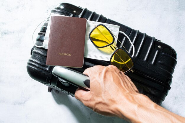 bagaglioPassaporto della valigia e maschera medica Passaporto in mano e tessera di vaccinazione approvata