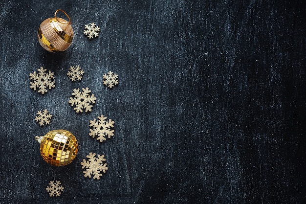 Bagattelle dorate con fiocchi di neve dorati sul nero. Lay piatto.