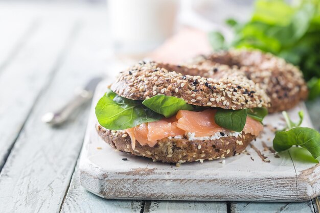 Bagel con crema di formaggio avocado, pesce, rucola e ravanello sul vecchio tavolo di legno. Cibo sano per la colazione.