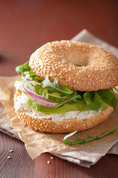 Bagel di avocado con crema di formaggio, cipolla, cetriolo e rucola