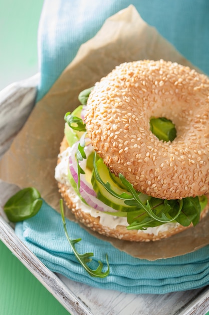 Bagel di avocado con crema di formaggio, cipolla, cetriolo e rucola