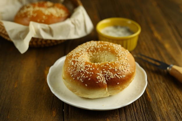 Bagel di sesamo con salsa di maionese nella tavola di legno