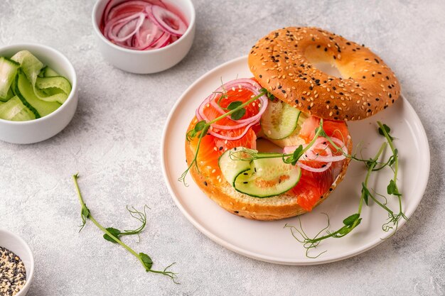 Bagel e salmone affumicato con crema di formaggio, cetrioli, cipolle e microgreens