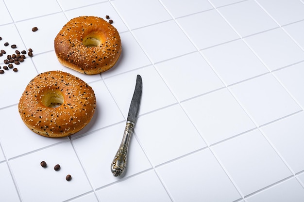 Bagel freschi con sesamo su sfondo bianco in ceramica quadrata piastrellata con spazio per la copia del testo