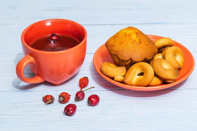 Bagel rotondi fatti in casa con muffin in un piatto arancione e tè al cinorrodo