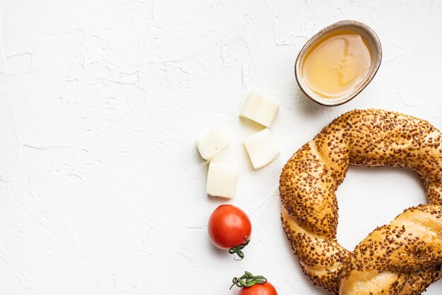 Bagel turco Simit con sesamo con ingredienti per la colazione formaggio di olive e pomodoro su sfondo tavolo in pietra bianca vista dall'alto piatto con spazio copia per il testo