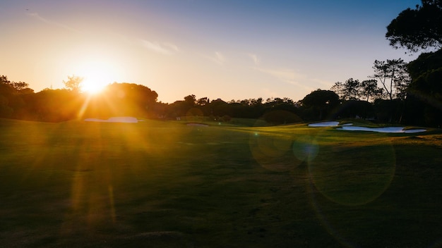 Bagliori di sole intenzionali Vista cinematografica del campo da golf vuoto illuminato d'oro nell'Algarve, Portogallo meridionale