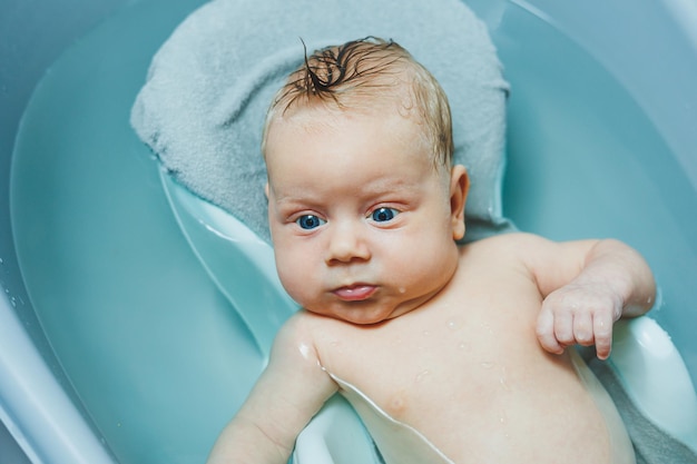 Bagnare un bambino in una vasca da bagno il bambino è sdraiato su un supporto di plastica cura del bambino