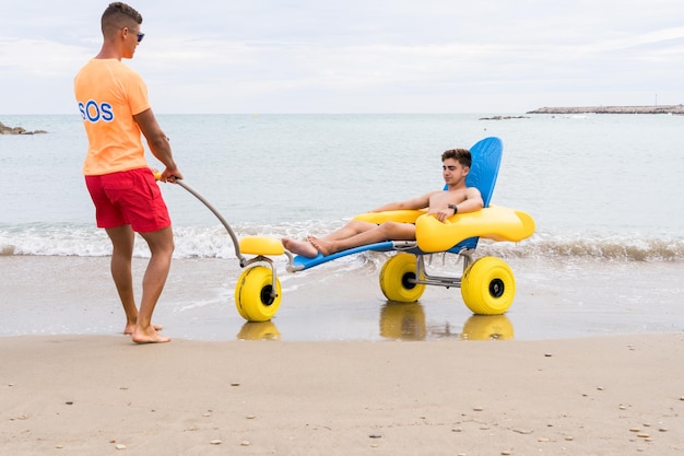 Bagnini che salvano un uomo ferito con una sedia con ruote sulla spiaggia