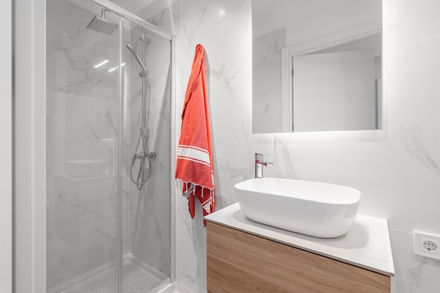 Bagno compatto bianco con lavandino con specchio e box doccia in vetro con un'elegante ristrutturazione