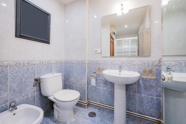 Bagno con cabina doccia con specchio smussato senza cornice in vetro sbiancato e piastrelle blu a mezza altezza