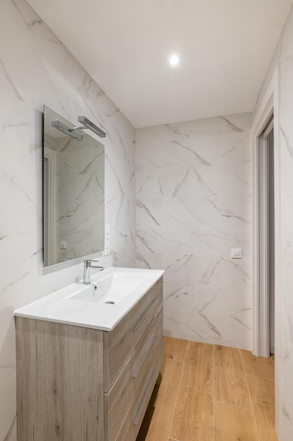 Bagno con lavabo in ceramica a specchio con piastrelle bianche sotto un armadio in una casa moderna o in un ufficio