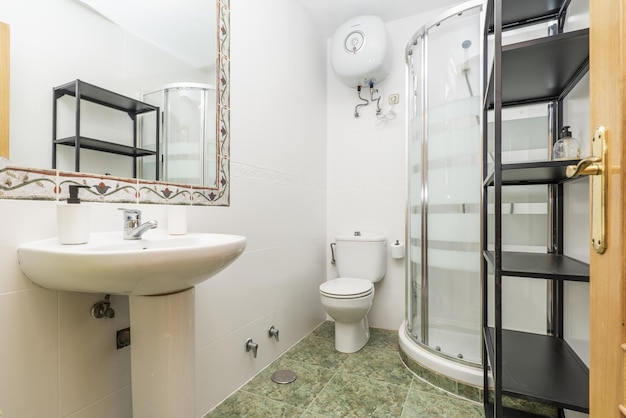Bagno con lavabo monoblocco in porcellana bianca e box doccia ad angolo con specchio a parete con mantovana e mensole in metallo nero