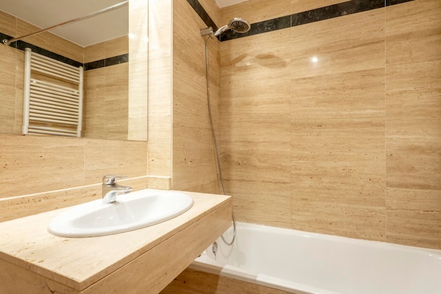 Bagno con piastrelle in marmo crema e sanitari in porcellana bianca con specchio incorporato senza cornice