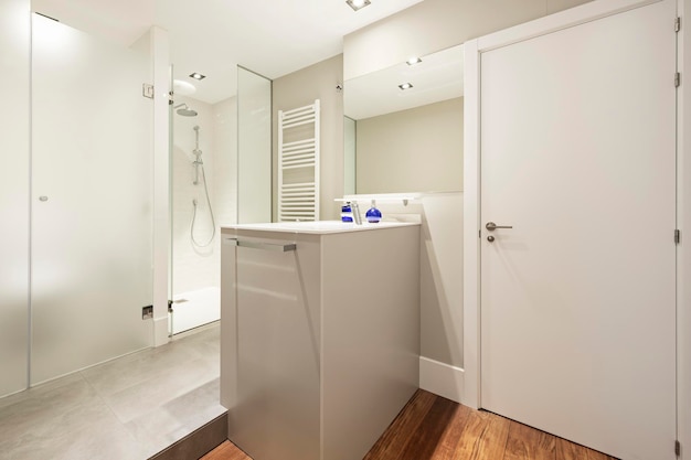 Bagno di lusso in casa vacanza con doccia separata e isola WC con lavandino pavimento in legno e pareti in tenui toni di grigio