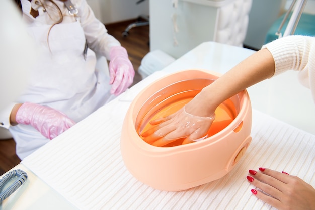 Bagno di paraffina. Salone termale. Manicure. Processo di trattamento con paraffina.