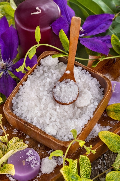 Bagno di sale in una ciotola di legno con fiori e foglie sullo sfondo