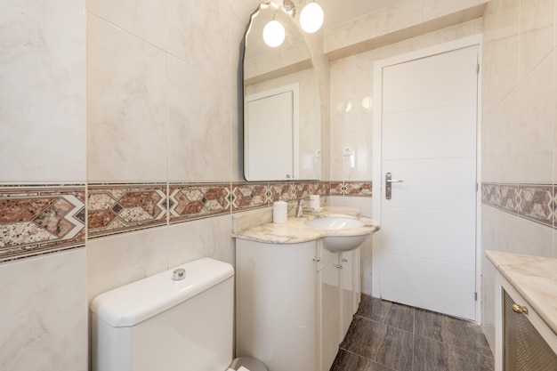 Bagno in stile decorato con mobili laccati bianchi con piano in marmo crema specchio bisellato sulla parete e bordo centrale sulle piastrelle