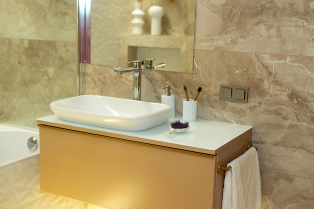 Bagno moderno nei toni del beige con piastrelle in marmo e lavabo bianco. Interior design. Messa a fuoco selettiva morbida, rumore artistico