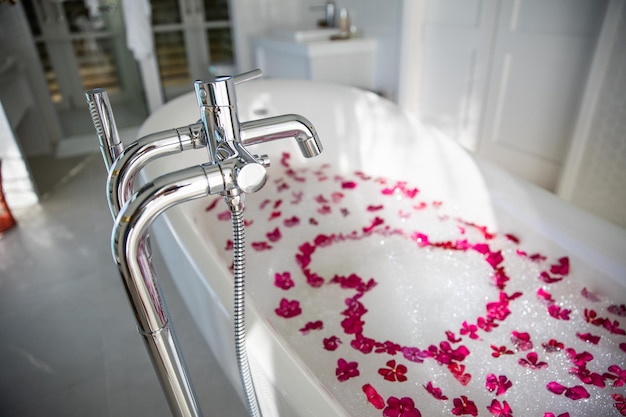Bagno romantico serale Per le coppie innamorate vasca idromassaggio sfocata e fiore rosa che forma la forma del cuore