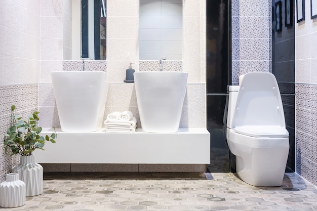 Bagno spazioso moderno con piastrelle luminose con servizi igienici e lavandino. Vista laterale