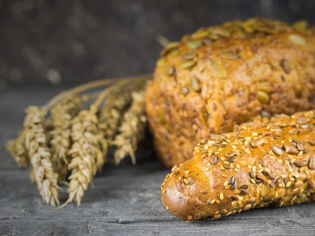 Baguette appena fatte e una pagnotta di farina di grano con spighe di grano su un tavolo rustico