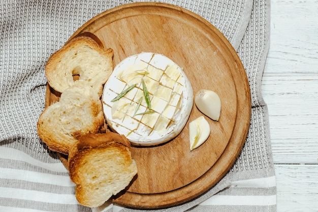 Baguette bianca tagliata a pezzi con olio d'oliva e Camembert sul tavolo