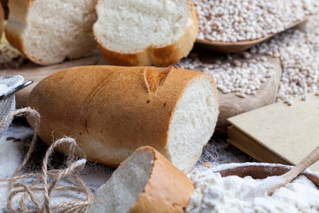 Baguette di frumento sul tavolo con farina e grani vegetali vari