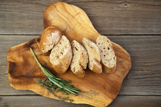 Baguette di grano intero tritato con erbe su una tavola di legno