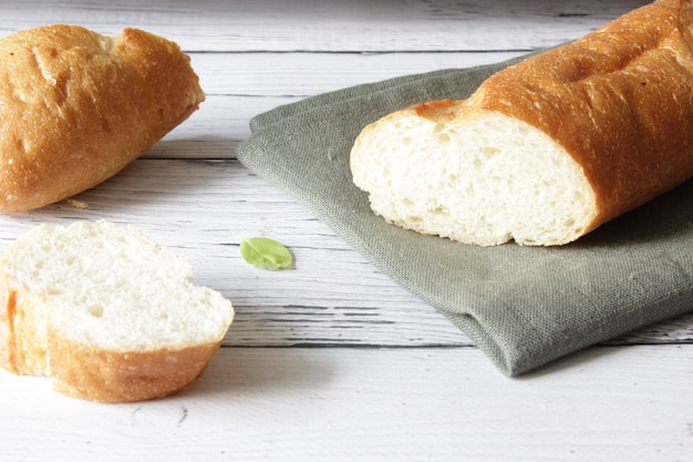 Baguette di pane morbido fresco francese sul tovagliolo e sullo sfondo di legno