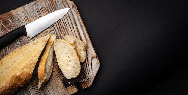 Baguette francese per bruschette affettate con coltello su tavola di legno primo piano pane croccante rustico f